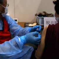 A health care worker administers a dose of the Pfizer-BioNTech COVID-19 vaccine at an inoculation site in Osaka on Tuesday. | BLOOMBERG