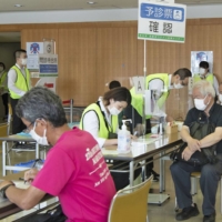 Older people gather at a mass vaccination site that opened in the city of Saitama on Tuesday. Japan will expand COVID-19 vaccinations to workplaces on June 21. | POOL / VIA KYODO