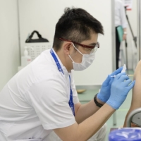 A medical worker administers a dose of the Moderna Inc. COVID-19 vaccine at a mass vaccination site in Tokyo on Wednesday.  | BLOOMBERG