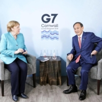 Prime Minister Yoshihide Suga and German Chancellor Angela Merkel hold talks in Cornwall, United Kingdom, on Saturday. | POOL / VIA KYODO