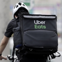 An Uber Eats delivery courier rides a bicycle along a street to make a delivery in Tokyo in April 2020.  | BLOOMBERG