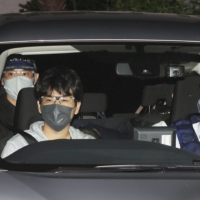 Kazutaka Hayashi, 40, ducks while being transported to a police station in Omiya, Saitama Prefecture, late Friday. Hayashi was arrested at an internet cafe after holding a female worker hostage for more than 32 hours in a small room, police said. | KYODO