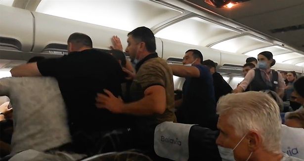 A throng of men formed in the aisle of the plane