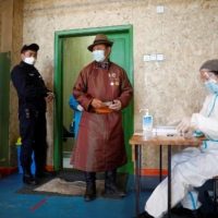 A man wearing a face mask waits at a polling station during the presidential election in Ulaanbaatar, Mongolia, on Wednesday. | REUTERS