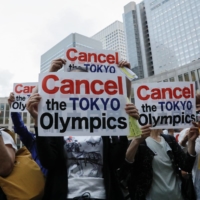 People hold signs at a rally calling for the cancellation of the 2020 Olympic Games, one month from the official start of the games, in front of the Tokyo Metropolitan Government office on June 23. | REUTERS