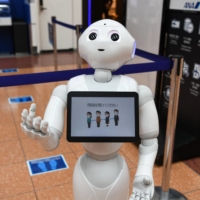 A SoftBank Group Corp. Pepper humanoid robot at Haneda Airport in Tokyo reminds travelers to social distance. | BLOOMBERG