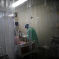 A medical worker wearing personal protection equipment treats a patient suffering from the coronavirus disease in the Intensive Care Unit of St. Marianna University Yokohama Seibu Hospital, in Yokohama on May 25. | REUTERS