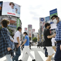 Pedestrians cross the scramble crossing in Tokyo's Shibuya Ward on Friday.  | KYODO