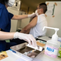 A health worker administers the Moderna COVID-19 coronavirus vaccine during the first round of vaccinations for firefighters in Tokyo on June 8. The capital reported 337 new cases of COVID-19 on Tuesday. | AFP-JIJI