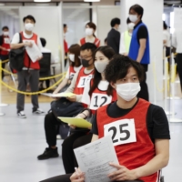 SoftBank Group Corp. employees take part in a COVID-19 vaccination simulation at the WeWork Nogizaka coworking office in Tokyo on Friday. | BLOOMBERG