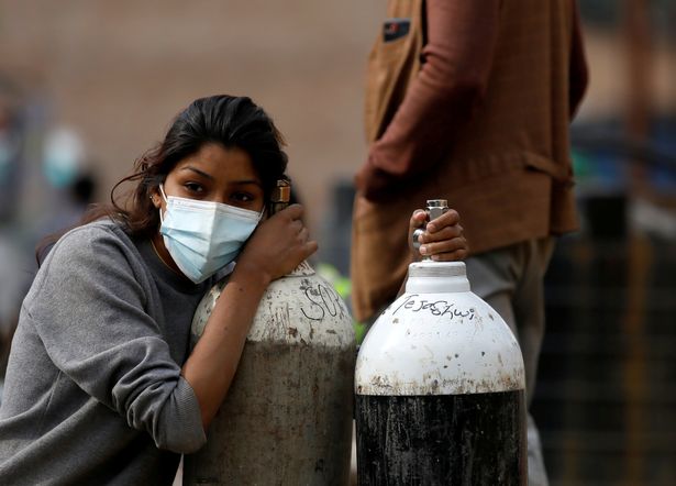 A woman holds on to the oxygen cylinders for a patient