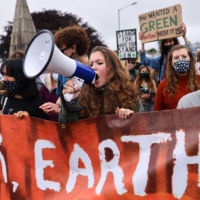 A woman holds a megaphone during a climate protest in Falmouth, England, on Friday. | REUTERS