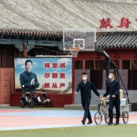 Members of the People's Liberation Army walk past a banner featuring a portrait of Chinese President Xi Jinping in Beijing last week.  | BLOOMBERG