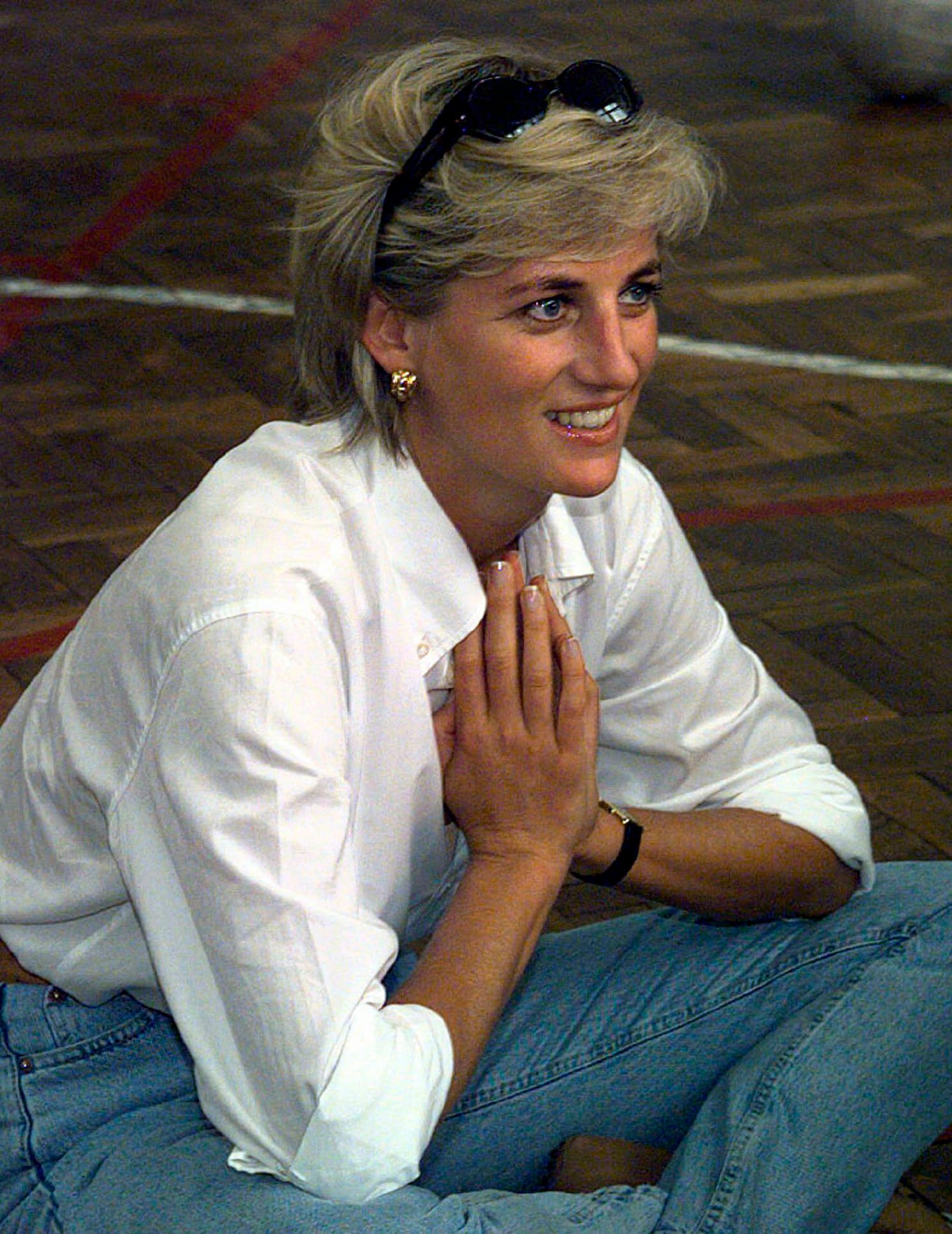 Princess of Wales, sits and talks to members of a Zenica volleyball team who have suffered injuries from mines, during her visit to Zenica, Bosnia. She believed in fashion classics for those informal minimalist looks. A white shirt with mommy jeans and gold earrings does the trick here. (AP)