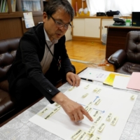 Jun Tashiro, the principal of Shiratori Elementary School, shows a chart listing problems that would need to be solved to taking students to watch the Olympic Games, during an interview at the school in Tokyo on June 30. | REUTERS