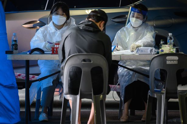 Health workers recieve visitors to a temporary COVID-19 novel coronavirus testing centre in Bucheon, south of Seoul, on May 27, 2020