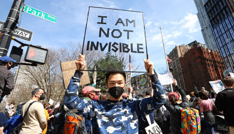 protester holds a sign that reads "I am not invisible"