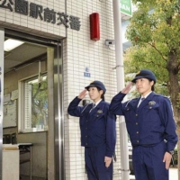 Reporting for duty: Two police officers give a salute in front of a police box in Tokyo's Daiba area.  | KYODO