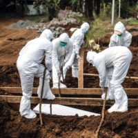 Gravediggers wearing personal protective equipment lower a coffin for burial at a cemetery in Bogor, Indonesia, on Sunday as the country grapples with the highly infectious delta variant of COVID-19. | AFP-JIJI