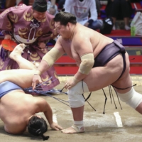 Terunofuji (right) slaps down Tobizaru during Day 8 of the Nagoya Basho on Sunday at Dolphins Arena. | KYODO