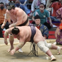 Yokozuna Hakuho (left) throws down ozeki Terunofuji to win the Nagoya Grand Sumo Tournament with an undefeated 15-0 record on Sunday at Dolphins Arena. | KYODO