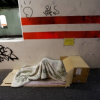 A homeless person sleeps on the street in Shibuya Ward, Tokyo, in 2017. | REUTERS