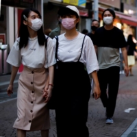 Women walk by a shop selling masks in Tokyo on Friday. | REUTERS