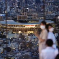 People pose for photos on an observation deck in Tokyo's Shibuya Ward on Tuesday with the National Stadium in the background. | KYODO