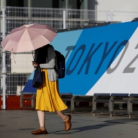 A woman walks past Tokyo 2020 Olympics sign at the Main Press Center in the capital on Friday. | REUTERS