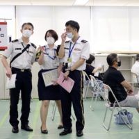 Self-Defense Force members work at a state-run mass vaccination site in Tokyo on June 9. The SDF will extend the opening period for the venues it operates in Tokyo and Osaka for about a month until late September, sources said Sunday. | POOL / VIA REUTERS