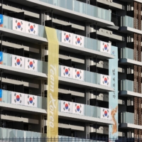 South Korean flags and signs hang on an apartment building hosting Olympics participants at the athletes' village in Tokyo on Saturday.  | REUTERS