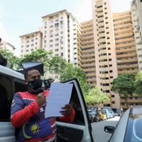 An officer uses a loudspeaker to remind people to stay at home during an enhanced lockdown due to the COVID-19 outbreak in Kuala Lumpur on July 3. | REUTERS