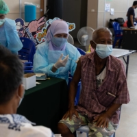 A health care worker administers a dose of the AstraZeneca COVID-19 vaccine at a vaccination center set up at Phuket International Airport in Phuket, Thailand, on June 27. | BLOOMBERG