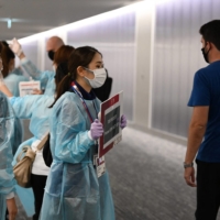 Airport workers wait for Olympic athletes and officials arriving on a flight from Doha, at Narita Airport in Chiba Prefecture on Wednesday. | AFP-JIJI