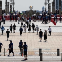 People walk on the Ariake Yume-no-Ohashi Bridge where the Olympic cauldron is placed for the Olympic flame in Tokyo on Saturday. | AFP-JIJI