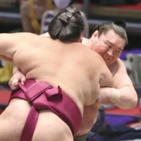 Mitakeumi (front) squares off against Hakuho in Nagoya on Thursday. | KYODO