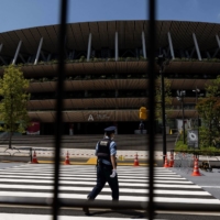 A police officer walks inside the closed area of the National Stadium, the main venue for the Tokyo 2020 Olympic and Paralympics, in the capital on Saturday.  | AFP-JIJI