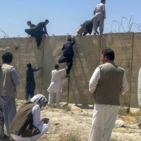 Men try to get inside Hamid Karzai International Airport in Kabul on Monday. | REUTERS