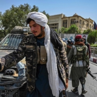 Taliban fighters stand guard along a street at the Kabul's Massoud Square on Monday. | AFP-JIJI