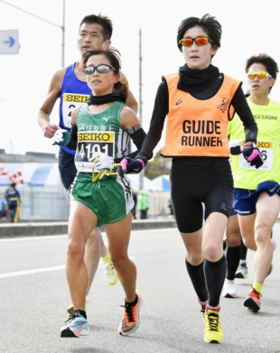 Visually impaired athletes run with a guide. The guide runs alongside the athlete, holding one end of a rope with a loop that is called a tether. The visually impaired person holds the other end of the rope and keeps pace. | KYODO