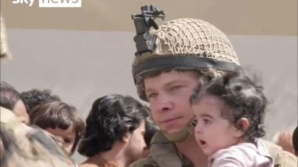 The unnamed soldier holds onto a child whose parents are trying to get the family out of the country