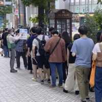 People line up in Tokyo's Shibuya Ward on Sunday to obtain a lottery ticket to get vaccinated. | KYODO