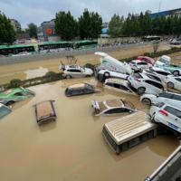 Cars are swept away floodwaters in the city of Zhengzhou, in China's central Henan province, on July 21. | AFP-JIJI