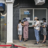 Residents queue at a COVID-19 testing facility in Beijing on Monday. | BLOOMBERG