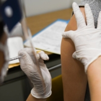 A health care worker administers a dose of Moderna Inc.'s COVID-19 vaccine at a mass vaccination site in Saitama on Aug. 23. | BLOOMBERG