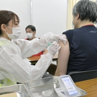 A man receives a shot of AstraZeneca PLC's COVID-19 vaccine at a mass vaccination center in the city of Osaka on Monday. | POOL / VIA KYODO