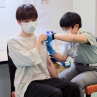 A Tokyo Fire Department member of staff administers a dose of the Pfizer-BioNTech COVID-19 vaccine at Aoyama Gakuin University's Aoyama campus in Shibuya Ward, Tokyo, on Aug. 2.  | STANISLAV KOGIKU /SOPA IMAGES/ VIA BLOOMBERG