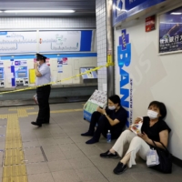 A train station staff member stands near passengers at the site where a stabbing incident occurred on a train, at the Soshigaya-Okura station of the Odakyu Electric Railway in Setagaya Ward, Tokyo, on Friday. | REUTERS