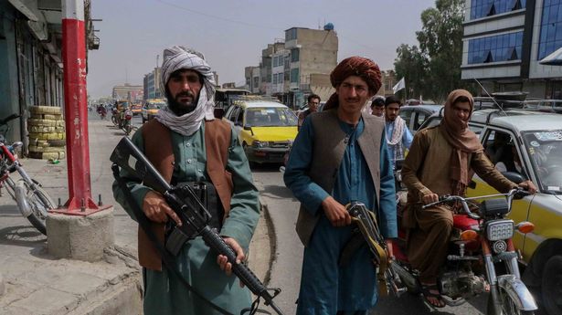 Taliban fighters stand guard at a checkpoint in Kandahar