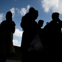 Refugees from Afghanistan wait to board a bus after arriving and being processed at Dulles International Airport in Dulles, Virginia, on Monday. | AFP-JIJI